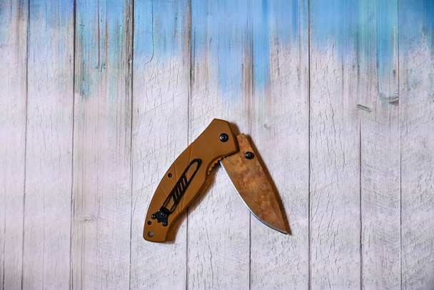 folding knife on wooden background in blue - Photo, Image
