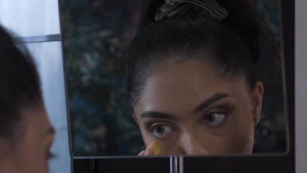 Jovem mulher usando misturador de beleza em torno de olhos olhando no espelho. Bloqueado - Filmagem, Vídeo