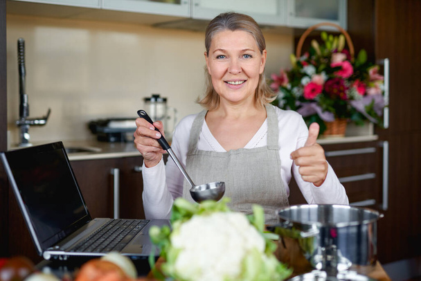 Reife Frau in Küche bereitet Essen zu. - Foto, Bild