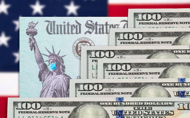 Деньги и стимулирование налоговой службы США Проверка статуи Свободы, носящей маску для лица на американском флаге. - Фото, изображение