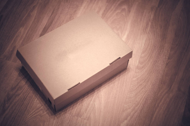 Картонна коробка для взуття без написів на дерев'яній підлозі в магазині
 - Фото, зображення