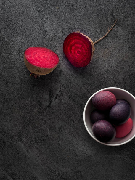 White bowl of Easter eggs colored naturally with everyday ingredient, beetroot. Overhead shot with copy space. Dark and moody. - 写真・画像