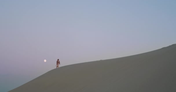 Mujer joven caminando en el desierto al amanecer sola - Imágenes, Vídeo