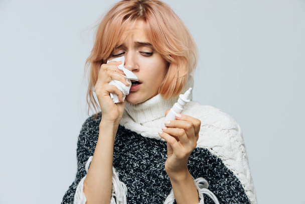 Słodka niezdrowa biała kobieta z papierową serwetką kichająca, używająca aerozolu do nosa, doświadcza objawów alergii, przeziębiła się. Zapalenie błony śluzowej nosa, przeziębienie, choroba, koncepcja alergii - Zdjęcie, obraz