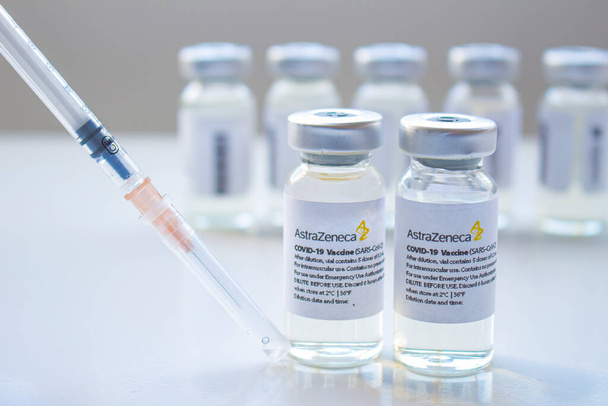 Calgary, Alberta, Kanada. Ocak 03, 2021. AstraZeneca Covid-19 aşılarının seçici odak noktası temiz bir arkaplanda şırınga ile şişeleri şişeler. - Fotoğraf, Görsel