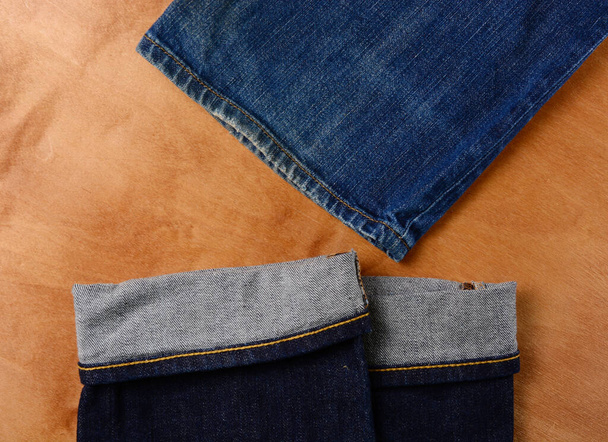 木製の背景に青いジーンズの断片。フラットレイアウト男性スタイル。ショッピングコンセプト。流行の衣装. - 写真・画像