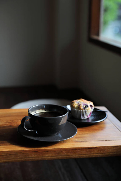 Kaffeetasse mit Muffin auf Holztisch in lokalem Café - Foto, Bild