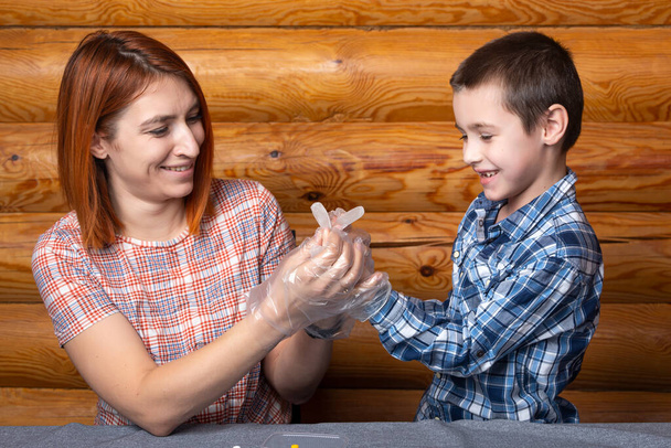 Little boy and mom put on disposable surgical gloves and get ready to do chemical experiments at home - Valokuva, kuva