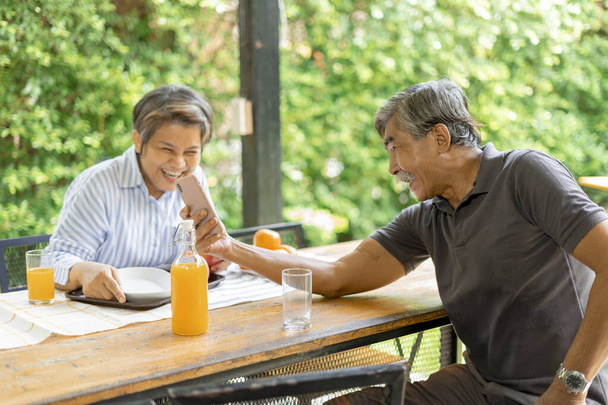 Idosos idosos idosos casal olhando para smartphone e rir no quintal ao ar livre. - Foto, Imagem