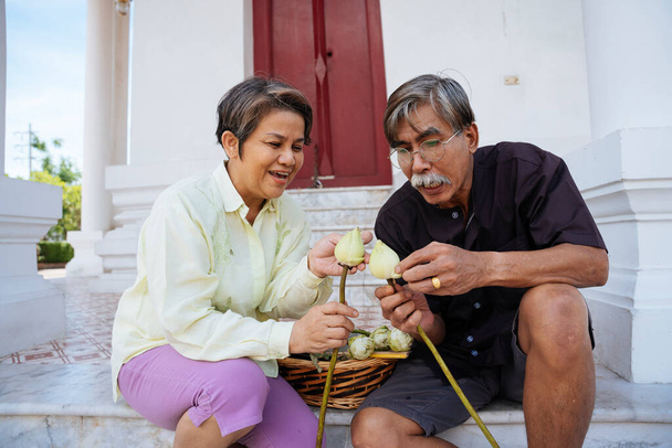 Asiatico anziani anziani vecchio coppia preparare loto fiore a fare un merito in tempio. - Foto, immagini