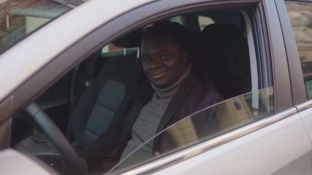 Ενθουσιασμένος Αφροαμερικάνος μαύρος εμφανίζεται με τον αντίχειρα ενώ κάθεται στη θέση του οδηγού του νέου του αυτοκινήτου - Πλάνα, βίντεο
