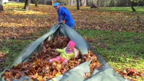 Homem louco pai puxar sua filha com folhas de outono na tenda. Criança feliz rindo - Filmagem, Vídeo