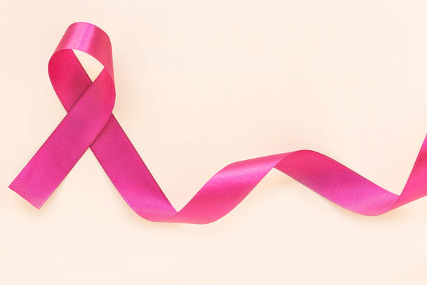 Red burgundy ribbon bow curl on isolated pastel beige background with copy space, symbol of Multiple Myeloma or Plasma cell cancer awareness. Healthcare or hospital and insurance concept. - Fotografie, Obrázek