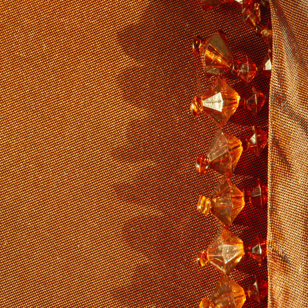 oro ámbar, tela de seda, decorado con perlas de vidrio amarillo, decoración decorada con perlas, tarjeta de diseño, textura de fondo - Foto, Imagen