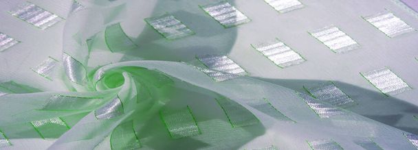 Textur, Hintergrund, Muster, Postkarte, Seidenstoff mit quadratischen Platineinsätzen aus Metall mit smaragdgrünen Linien, Aquamarin-Pastellfarben - Foto, Bild