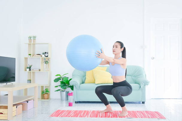 Asian sporty young woman doing exercise alone in living room. Workout at home. - Foto, imagen
