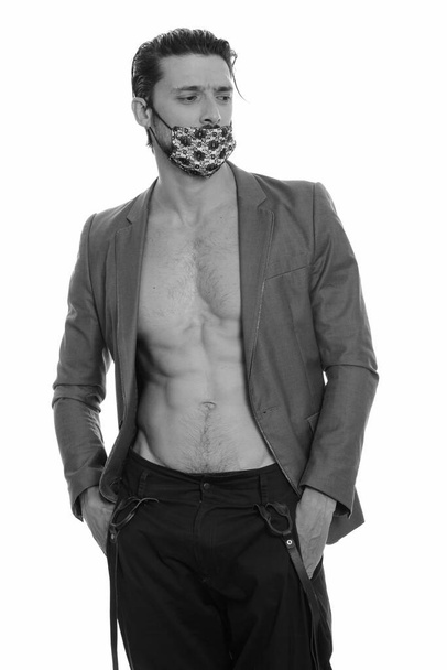 Ritratto di bell'uomo che indossa una maschera per proteggersi dall'infezione covid-19 sparata in bianco e nero - Foto, immagini