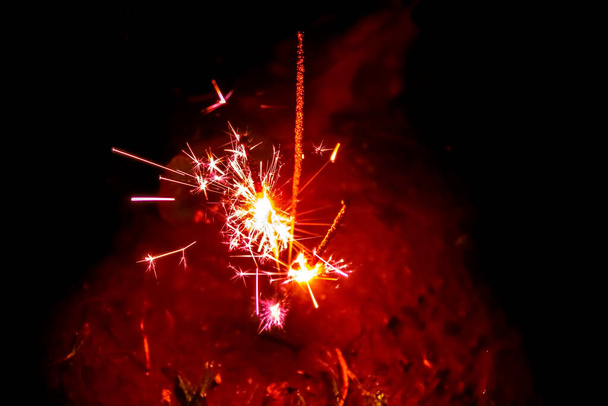 Feuerwerk, Wunderkerzen und Bokeh-Lichter auf dunkelblauem Hintergrund - Foto, Bild