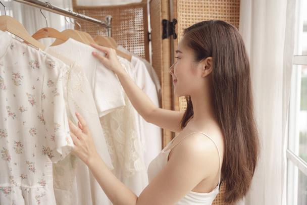 Genç Asyalı güzel kadın gardıropta beyaz gömlek seçiyor.. - Fotoğraf, Görsel