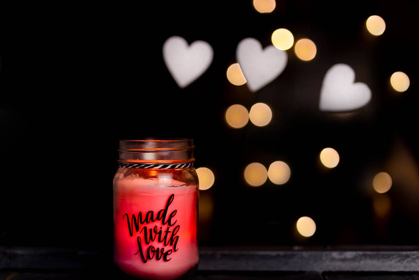 płonąca różowa świeca z napisem, wykonana z miłości, na ciemnym drewnianym tle z bokeh, Walentynki - Zdjęcie, obraz