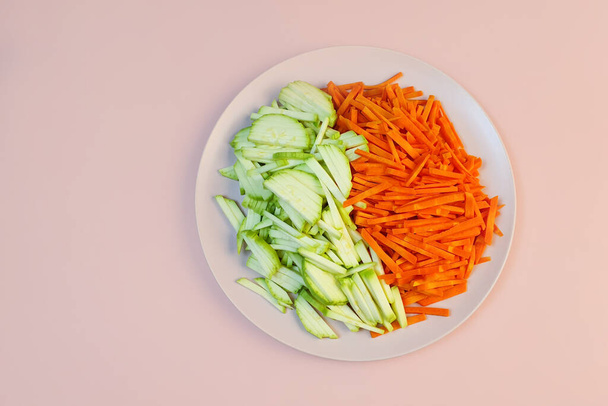 Trancher les carottes et les courgettes sur une assiette rose. Vue du dessus - Photo, image