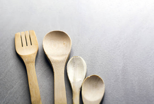 Gruppo di utensili da cucina in legno disposti su un tavolo in marmo grigio. Focus selettivo sulla forchetta da intaglio. - Foto, immagini
