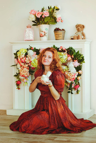Portrait of young redhead woman  with freckles in red dress sitting in spring day at home. Natural beauty. Woman's Day. Greeting card.  - Фото, зображення