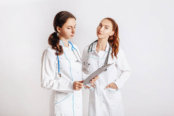 Medical documents. Two doctors with stethoscope at hospital. Nurse hold patient medical chart. Information data. Therapist in uniform. Medical history prescription. Woman work at clinic. - Photo, Image
