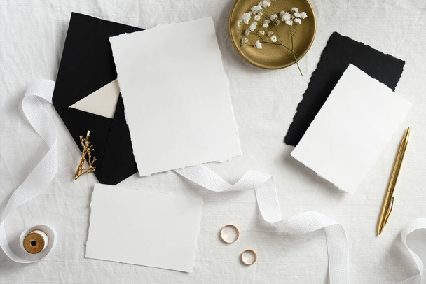 Wedding invitation cards design. Set of blank paper cards, black envelopes, golden decorations on white textile background. Elegant wedding stationery. - Photo, Image