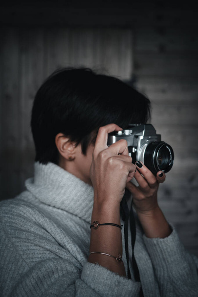 Фотограф тримає камеру плівки перед дерев'яною стіною
 - Фото, зображення