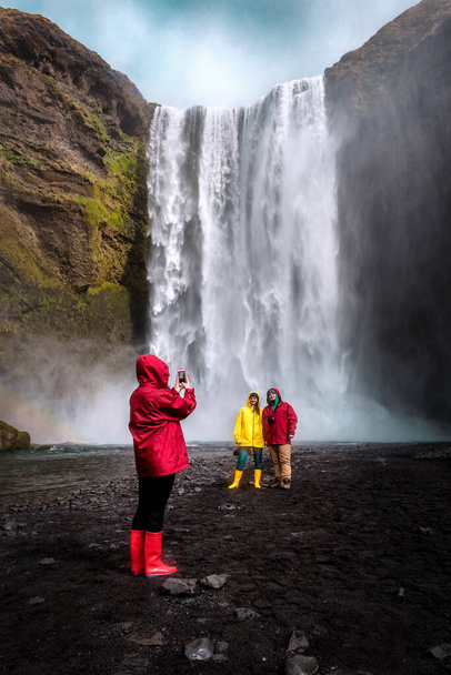 amis sont photographiés près de la cascade Skogafoss en Islande - Photo, image