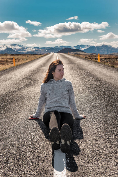 woman sitting on asphalt of the empty road - Photo, Image