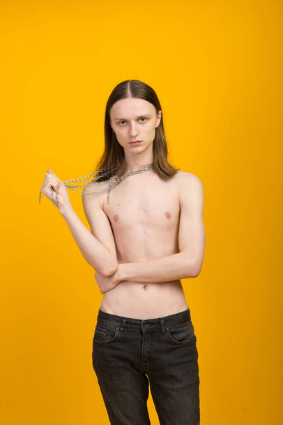 Androgyner schöner junger Mann. Modellversuche auf gelbem Hintergrund - Foto, Bild