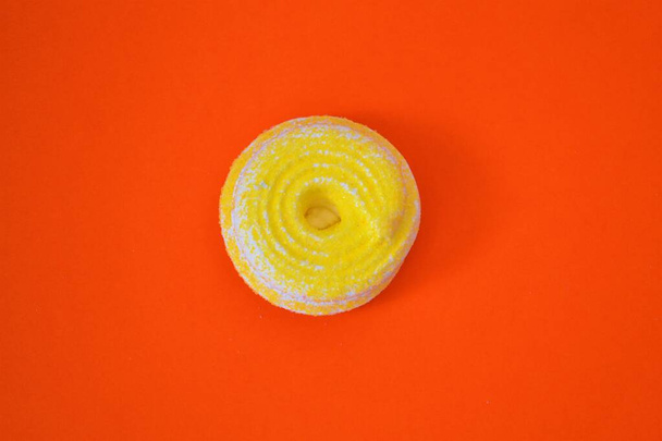 Spiral cookie made of yellow meringue on an orange background - Foto, afbeelding