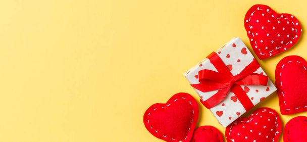 Σύνθεση διακοπών από κουτιά δώρων και κόκκινες υφασμάτινες καρδιές σε πολύχρωμο φόντο με κενό χώρο για το σχεδιασμό σας. Κάτοψη της έννοιας Ημέρα του Αγίου Βαλεντίνου. - Φωτογραφία, εικόνα