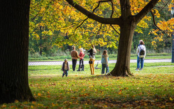 27.09.2020, Moscow, Russia. a group of tourists are photographed against the background of maple trees in the autumn park. People walking in the falling park. - Fotó, kép