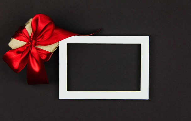 gift for black Friday sale and Christmas. Box with a red ribbon on a black background card frame for copy space - 写真・画像