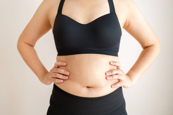 Femmes gros ventre. Main de femme obèse tenant la graisse du ventre excessive. concept de mode de vie diététique pour réduire le ventre et façonner le muscle de l'estomac sain. - Photo, image