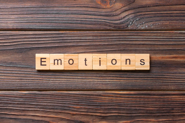 Слово EMOTIONS, написане на дерев'яному блоці. Текст EMOTIONS на цементній таблиці для вашого бажання, концепція
. - Фото, зображення
