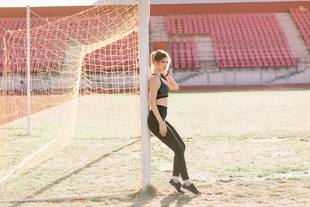 Young, beautiful girl athlete in sportswear is training and running, stretching at the stadium - Foto, Imagen