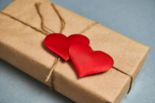 Koncept svatého Valentýna. Svatý Valentýn dárek v eko papíru a červené srdce na šedém pozadí - Fotografie, Obrázek