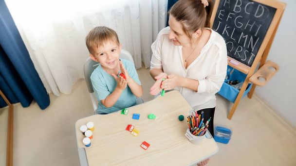 Top view photo of boy with mother shaping and sculpting colorful plasticine and clay. Family having fun with colorful toy dough - Φωτογραφία, εικόνα