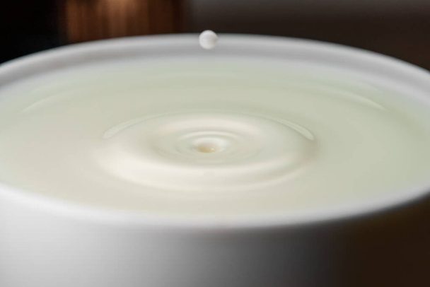La gota de leche cae en la taza llena. - Foto, Imagen
