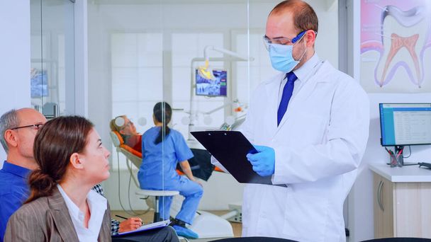 Médecin prenant des notes sur presse-papiers sur les problèmes dentaires des patients - Photo, image