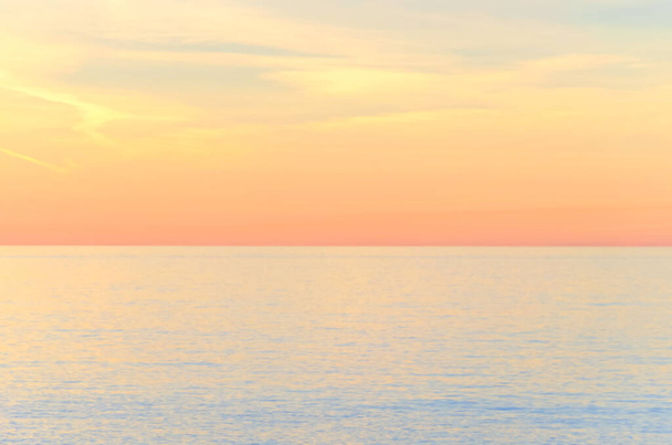 Ongefocuste wazige zonsondergang boven de zee in pastelkleuren. Natuurlijke warme kleuren natuurlijke gedefocuste achtergrond - Foto, afbeelding
