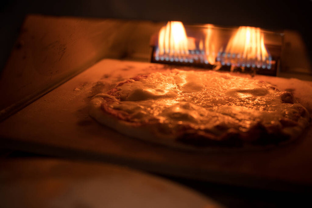 Detailní záběr na pizzu pečení v troubě. - Fotografie, Obrázek