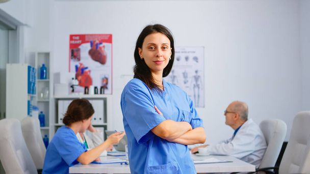 Νοσοκόμα που στέκεται μπροστά στην κάμερα χαμογελώντας - Φωτογραφία, εικόνα