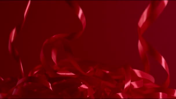 Szexi hangulat granátos fényes áramló szatén szalagok esik le a piros háttér. FHD még mindig készített kiváló minőségű videót. - Felvétel, videó