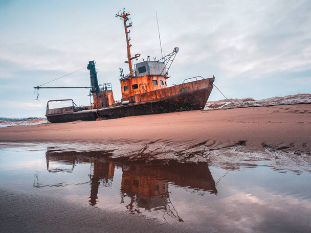 An old rusty fishing boat washed up on a sandy beach in the Barents Sea. Authentic the North sea. Teriberka. - Photo, Image