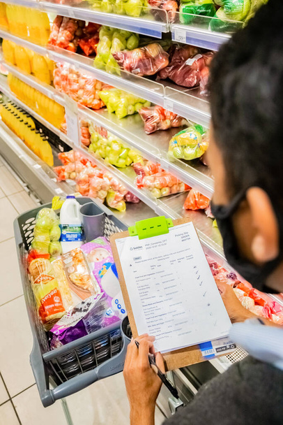 Cape Town, South Africa - December 10, 2020: Staff member picking grocery products from shelf for express home delivery service at local Pick n Pay supermarket  - Foto, Imagen